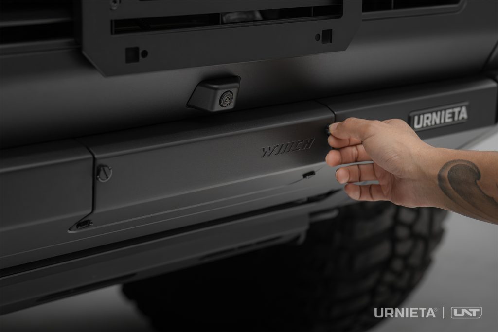 URNIETA LC250 Front Fascia Kit on a Toyota Land Cruiser 250, hand pulling the quick-release winch cover on the bumper